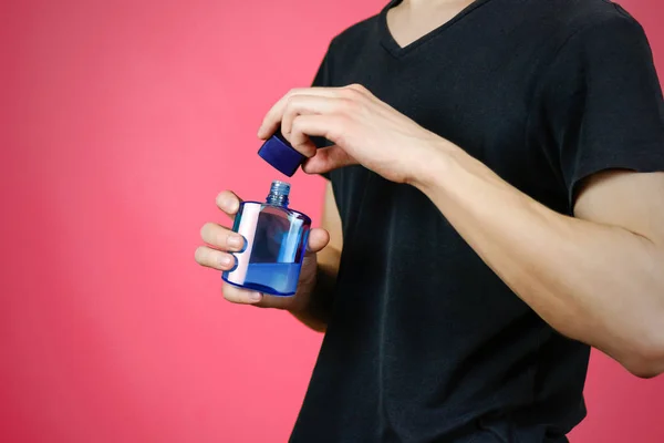 Man in het zwart t shirt blauw fles toilet water te houden. Close-up, — Stockfoto