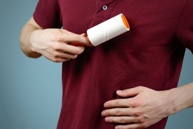 Bir adam t-shirt yapışkan rulo temizler. Portre. İzole