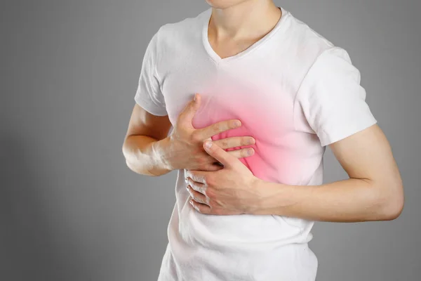 Un hombre sostiene los pechos. El dolor en el pecho. Ardor de estómago. Estoma — Foto de Stock