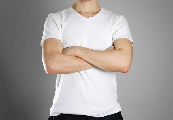 Homme en t-shirt blanc vierge. Le gars a plié les mains sur ses puces — Photo