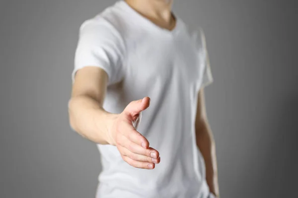 Un hombre con una camiseta blanca en blanco extiende su mano. El tipo dio la bienvenida —  Fotos de Stock