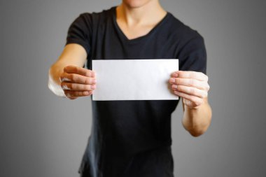 Beyaz bir sayfa tutan bir siyah tişörtlü adam. Boş el ilanı