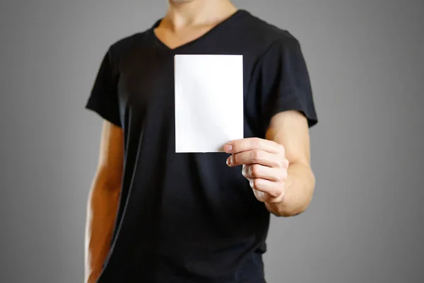 Mann in schwarzem Hemd mit weißem Blatt Papier in der Hand. leerer Flyer — Stockfoto