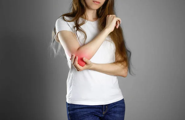 En kvinna håller armbågen. Smärtan i min arm. En öm punkt i rött — Stockfoto