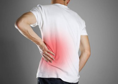 Beyaz t-shirt giyen sırtını tutunur. Ağrı alt b