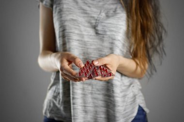 Kırmızı hapları paketlerinde tutan kız. Portre. Kabarcıklar Tablet