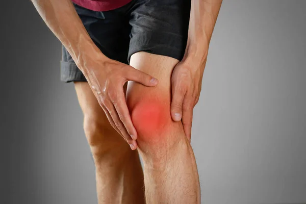 The guy clings to a bad knee. The pain in his leg. Closeup. The — Stock Photo, Image