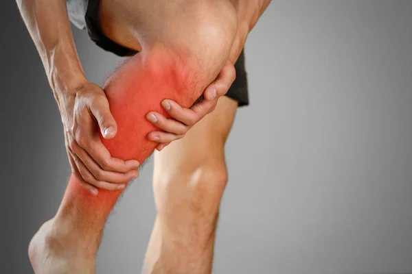 The guy clings to a bad knee. The pain in his leg. Closeup. The — Stock Photo, Image