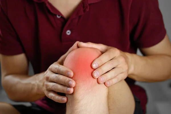 The guy clings to a bad knee. The pain in his leg. Closeup. The — Stock Photo, Image