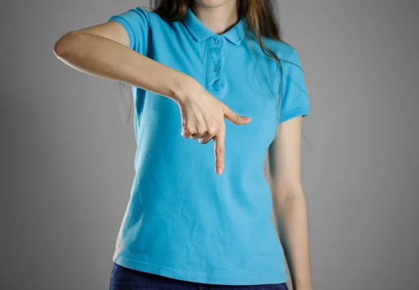 Девушка в синей футболке, указывающая пальцем вниз. Указывает — стоковое фото