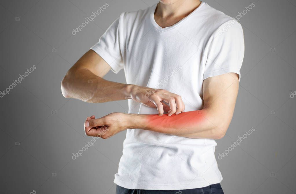 Guy in white shirt scratching his arm. Scabies. Scratch the hand