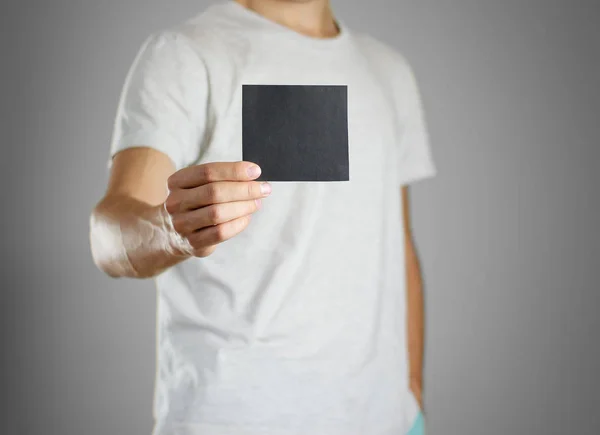 Um homem em uma camiseta cinza segurando branco preto claro da folha . — Fotografia de Stock