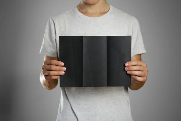 A man in a gray t-shirt holding blank clear black of the sheet. — Stock Photo, Image