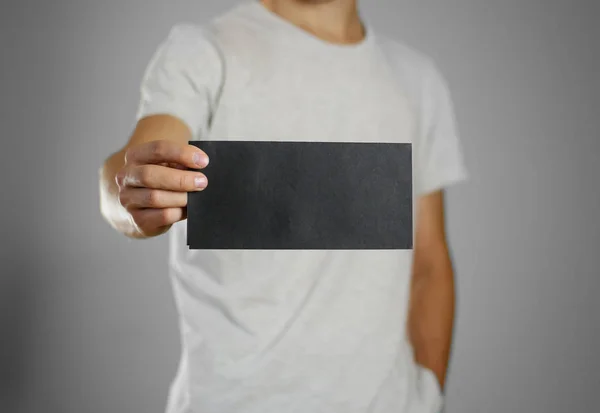 Un homme dans un t-shirt gris tenant blanc noir clair de la feuille . — Photo