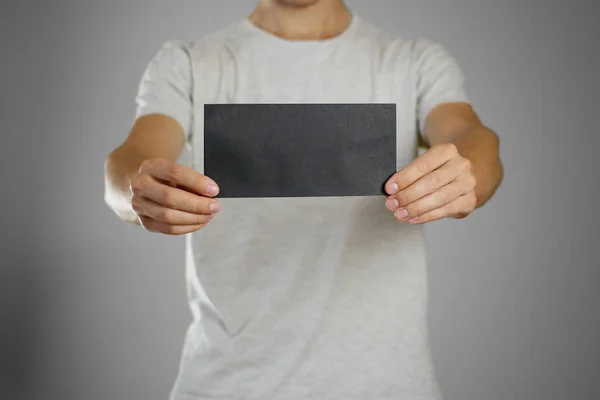 Чоловік у сірій футболці тримає порожній прозорий чорний лист . — стокове фото