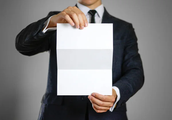 A man in black suit holding blank clear white of the sheet. Clos — Stock Photo, Image