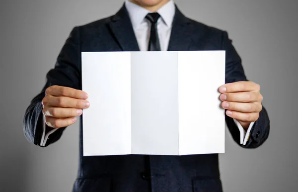 A man in black suit holding blank clear white of the sheet. Clos — Stock Photo, Image