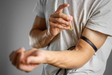 Genç bir adam kendini el şırıngada bir iğneyle enjekte eder wi