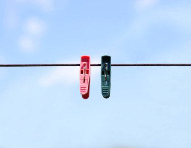 İp üzerinde yeşil ve kırmızı clothespins dönüştürün. Mavi arka plan üzerinde