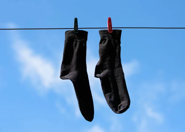 Zwarte sokken hang drogen aan de waslijn met wasknijpers. CLO — Stockfoto