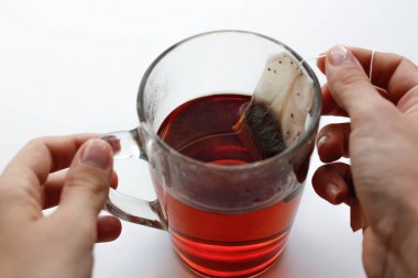 Şeffaf holding eller cam kupa ve bir çay poşeti. Bir fincan çay.