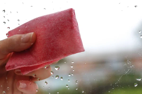 Kvinnas hand att torka droppar vatten på glas rosa tyg. Closeu — Stockfoto