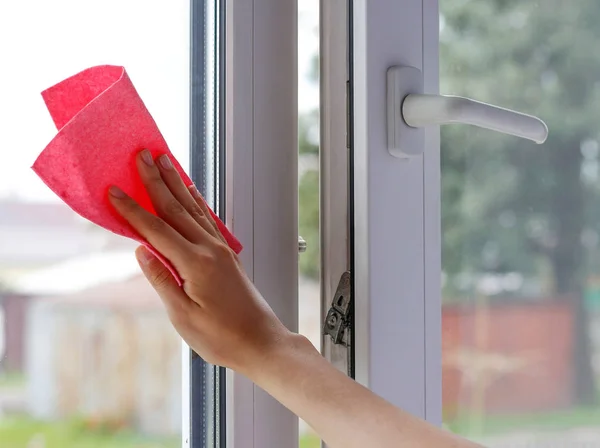 Hembra limpiando el vaso a mano. Lava la ventana de plástico blanco. Cierre — Foto de Stock