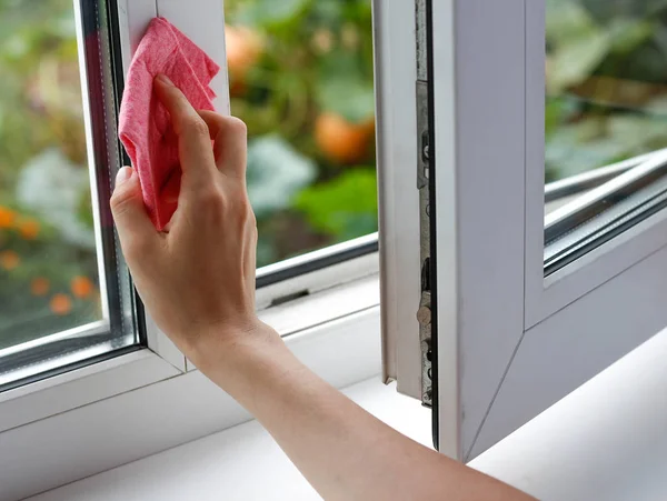 Hembra limpiando el vaso a mano. Lava la ventana de plástico blanco. Cierre — Foto de Stock