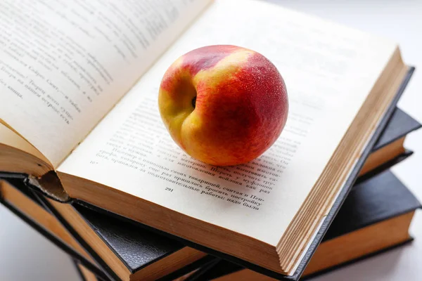 Peach ligger på fyra stora svarta böcker. Närbild — Stockfoto