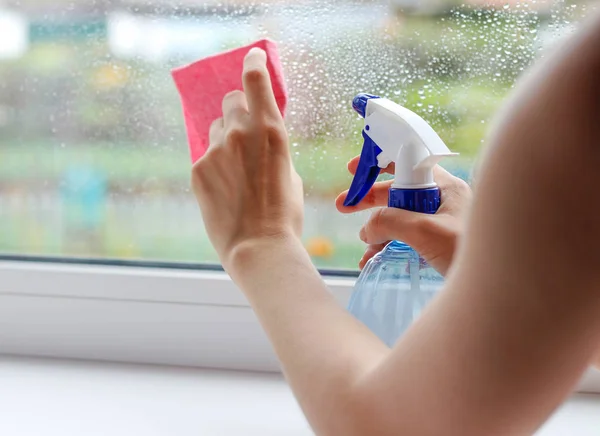 A menina lava a janela com um pano e spray salpicante. Fechar — Fotografia de Stock