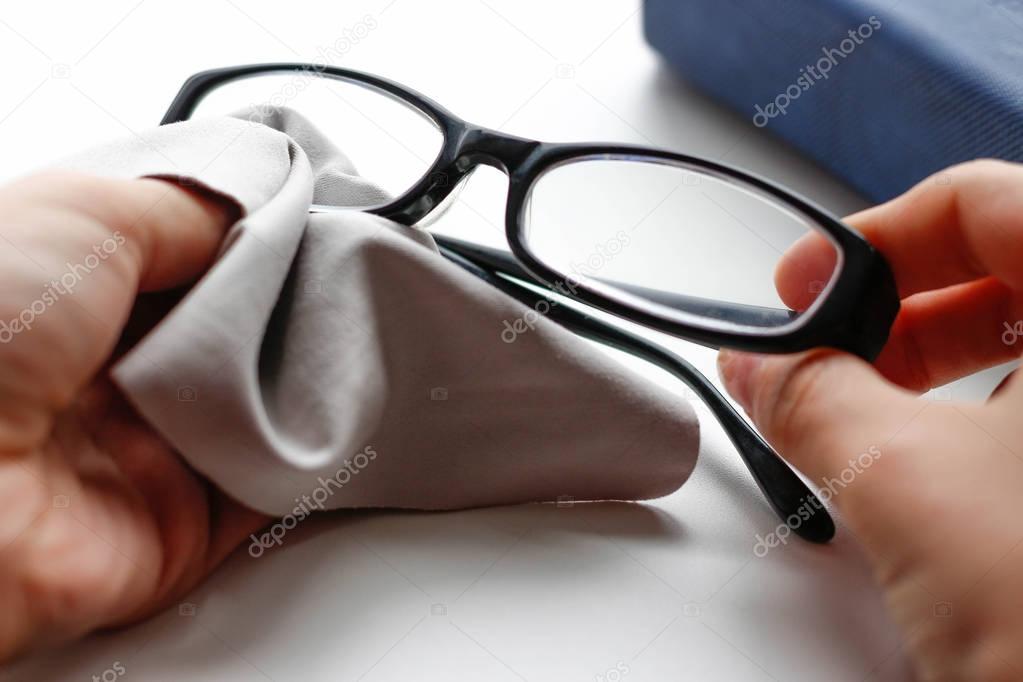 Glasses with black frame and grey wipe cloth. Closeup