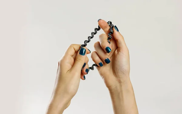 Weibliche Hand hält Plastikspirale scrunchie. isoliert auf grau — Stockfoto