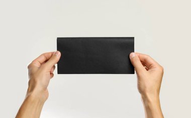 Erkek siyah parça kağıt tutan eller. Gri arkasında izole