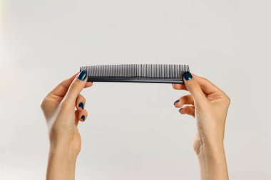 Siyah bir tarak tutan eller. Gri arka plan üzerinde izole. 