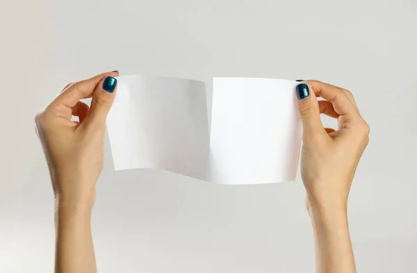Les mains féminines déchirent une feuille blanche de papier. Isolé sur fond gris — Photo