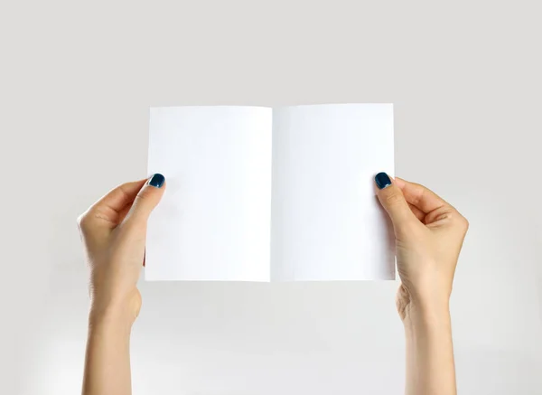 Des mains féminines tenant une feuille de papier blanche. Isolé sur ba gris — Photo