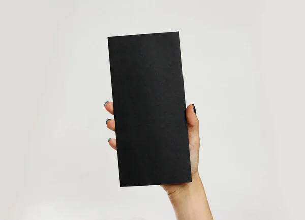 Female hands holding a black sheet of paper. Isolated on gray ba — Stock Photo, Image