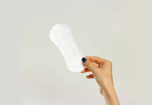 Kvinnliga händer som håller en vit sanitära pad. Isolerade på grå baksida — Stockfoto
