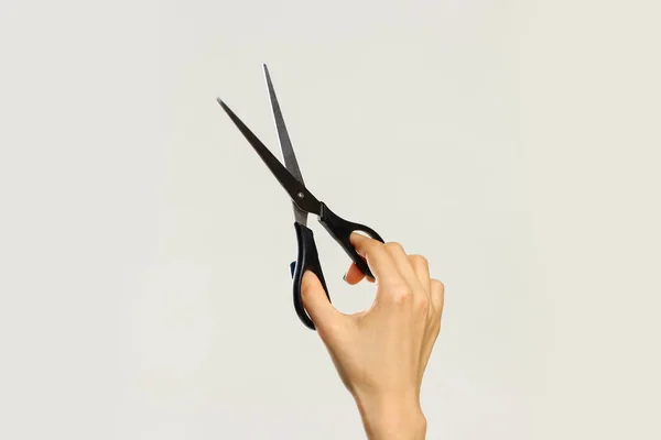 Female hands holding black scissors. Isolated on gray background — Stock Photo, Image