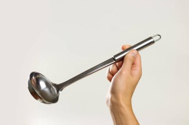 Erkek metal bir kepçe tutan eller. Gri arka plan üzerinde izole. C