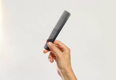 Erkek siyah bir tarak tutan eller. Gri arka plan üzerinde izole. CL