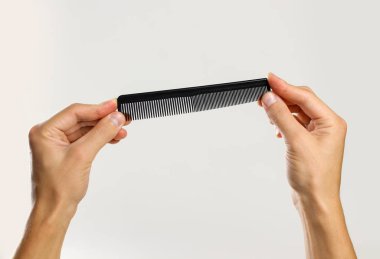 Erkek siyah bir tarak tutan eller. Gri arka plan üzerinde izole. CL