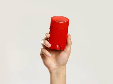 Erkek kırmızı deodorant tutan eller. Gri arka plan üzerinde izole. C