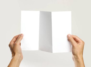 Beyaz bir kitapçık holding erkek eller kağıt üçlü. Isolat