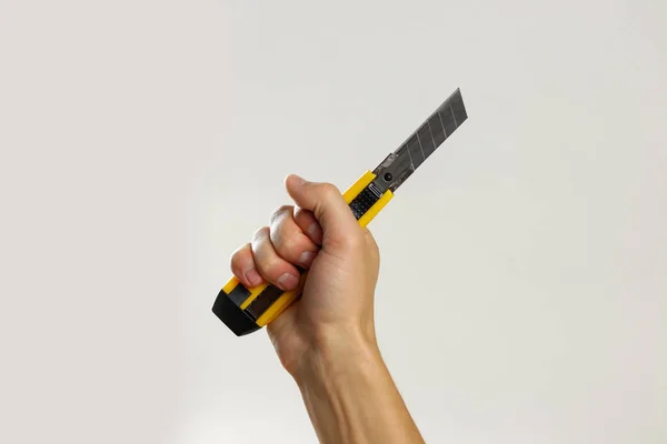 Mãos masculinas segurando cortador de caixa afiada amarelo. Isolado em bac cinza — Fotografia de Stock