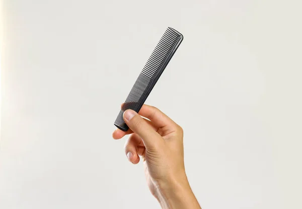 Male hands holding a black comb. Isolated on gray background. Cl — Stock Photo, Image