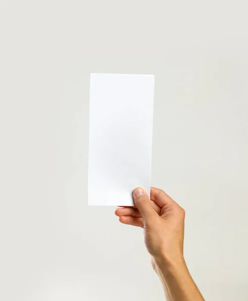 Αρσενικό χέρια κρατώντας ένα λευκό φύλλο χαρτί. Απομονωμένα σε γκρι πίσω — Φωτογραφία Αρχείου