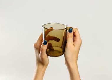 Siyah boş bardak kupa tutan el. Gri arkasında izole