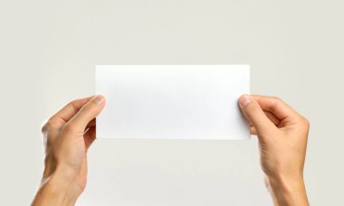 Erkek beyaz bir sayfa tutan eller. Gri arkasında izole