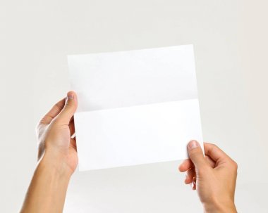 Erkek beyaz bir sayfa tutan eller. Gri arkasında izole